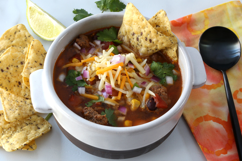 Instant Pot taco soup with tortilla chips and garnishes.