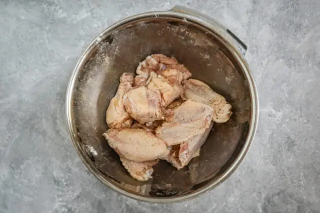 Air fryer chicken wings in a bowl with Parmesan cheese and parsley garnish.