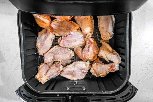 Chicken wings in the air fryer basket for air fryer garlic Parmesan wings.