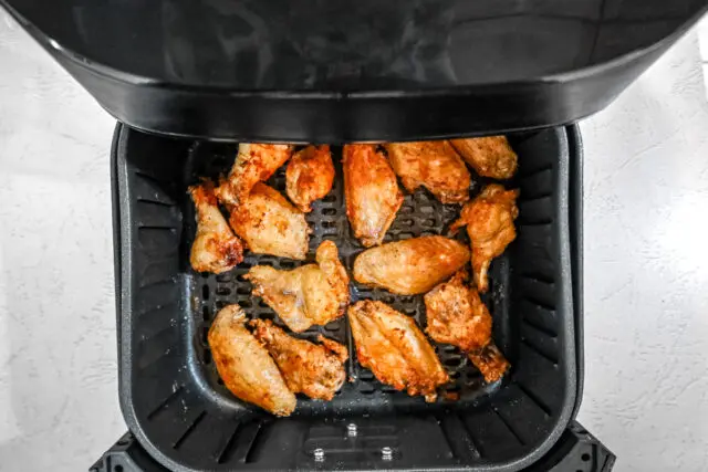 Cooked wings in the basket of the air fryer.