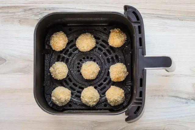 The potato croquettes are arranged in the air fryer basket.