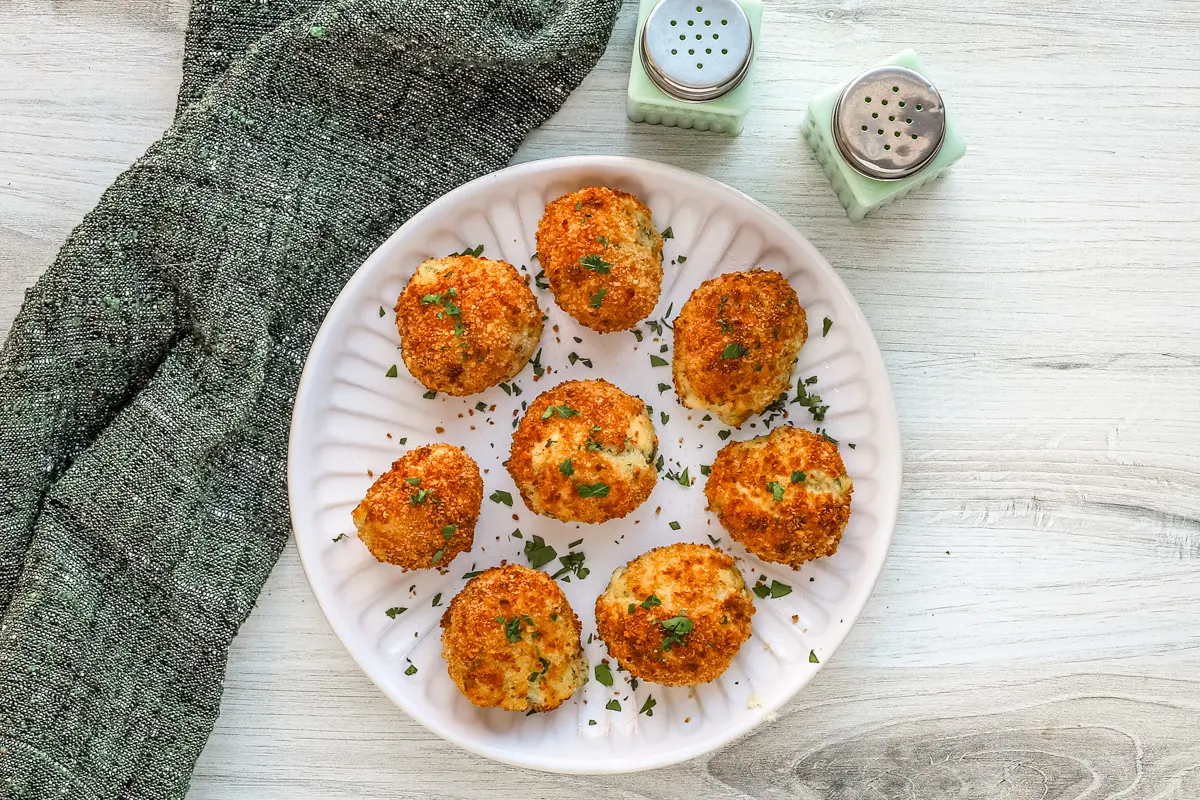 A plate of homemade air fryer potato croquettes made with leftover mashed potatoes, cheese, and herbs.