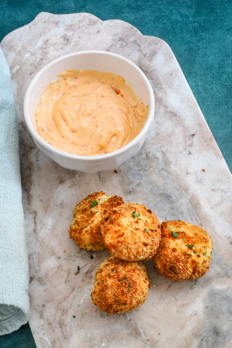 A plate of homemade air fryer potato croquettes made with leftover mashed potatoes, cheese, and herbs, and a dip on the side