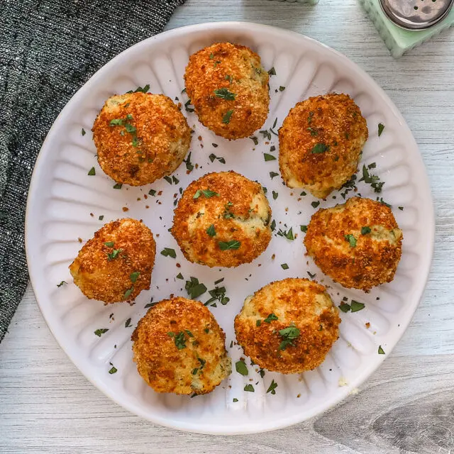 A plate of homemade air fryer potato croquettes made with leftover mashed potatoes, cheese, and herbs.