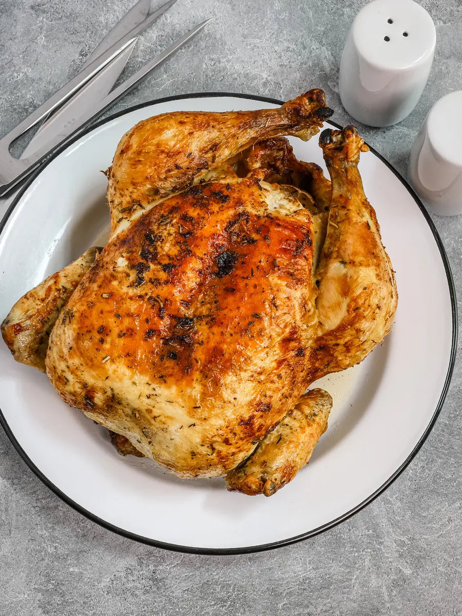 Air fryer whole roasted chicken on a plate, from Classic-Recipes.com.