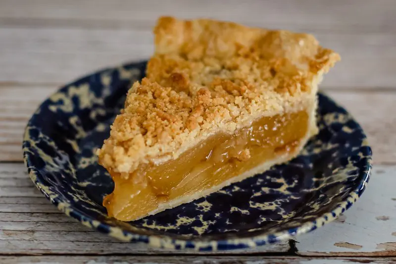 A slice of apple crumble pie on a plate.