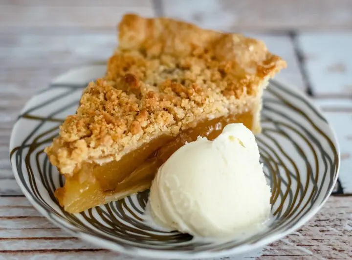 A slice of apple crumble pie with a scoop of ice cream.