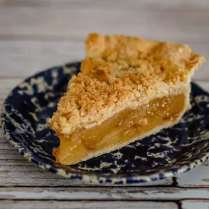 A slice of apple crumble pie on a blue plate.