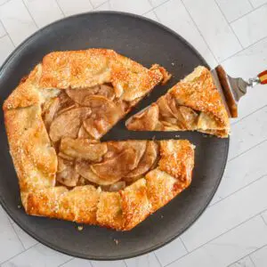 apple galette on a plate with a wedge cut out