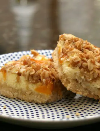 apricot cream cheese bars with shortbread crust and crumb topping, on a plate