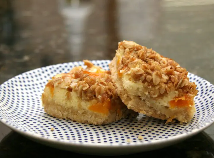 apricot cream cheese bars with shortbread crust and crumb topping, on a plate