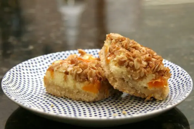 apricot cream cheese bars with shortbread crust and crumb topping, on a plate