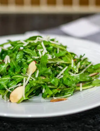 simple arugula salad with sliced almonds on a plate