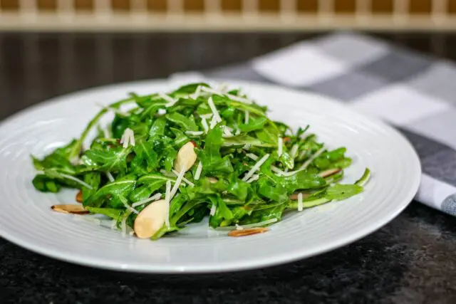 simple arugula salad with sliced almonds on a plate