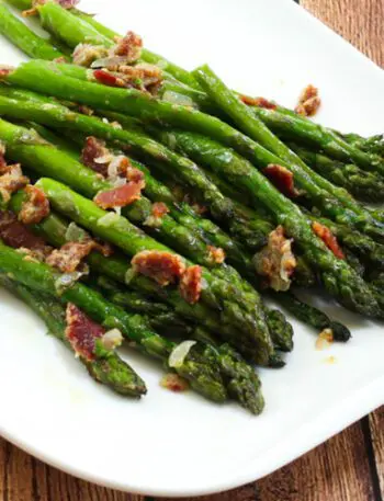 a plate of asparagus with bacon and light mustard sauce for flavor