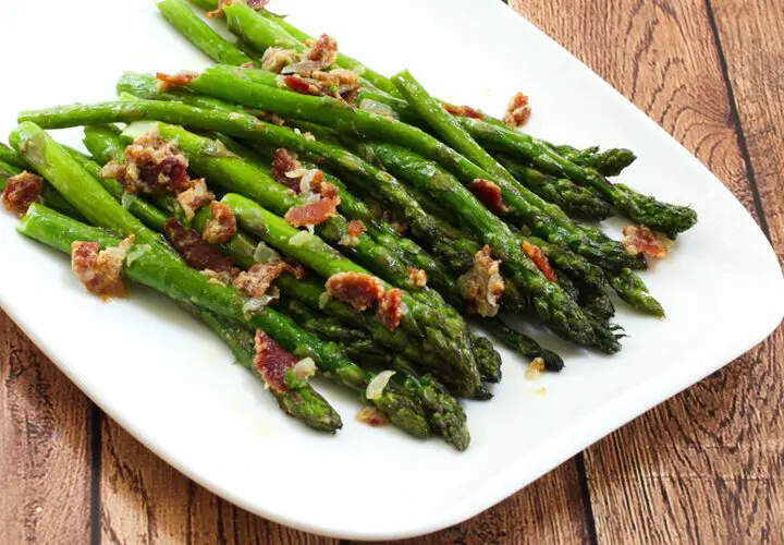 a plate of asparagus with bacon and light mustard sauce for flavor