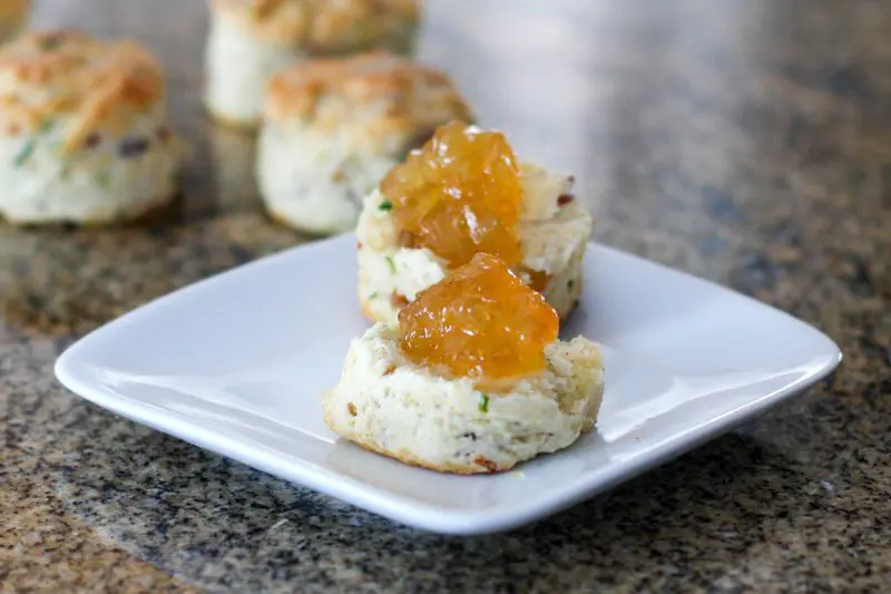 bacon and chive biscuits on a plate, topped with marmalade.