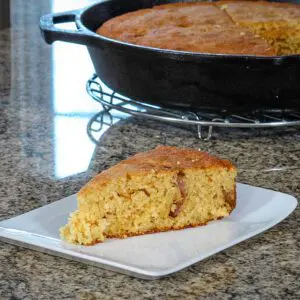 bacon and cheddar cornbread in a skillet with one slice on a plate