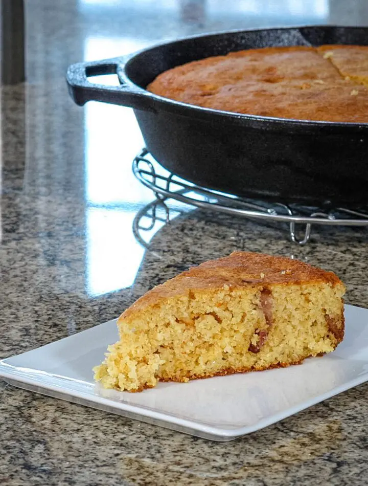 bacon and cheddar cornbread on a plate with the skillet in the background