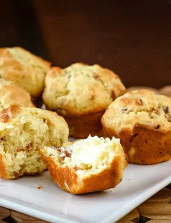 bacon muffins on a square plate, one is buttered