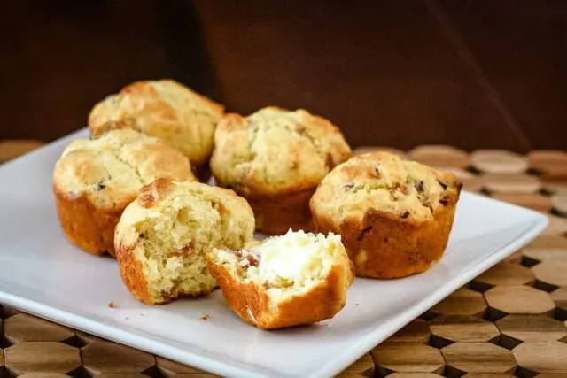 bacon muffins on a square plate, one is buttered