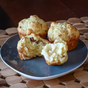 bacon muffins on a plate, with one muffin split and buttered.