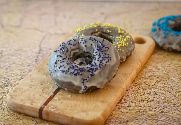 baked chocolate donuts with glaze and sprinkles on a small cutting board