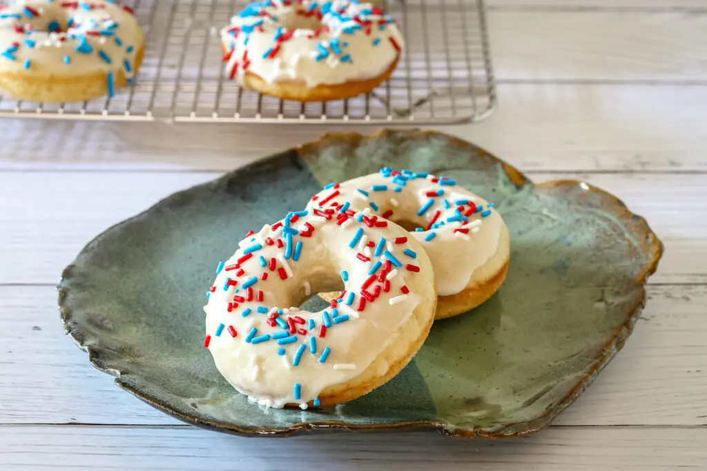 baked donuts on a plate with vanilla glaze and sprinkles