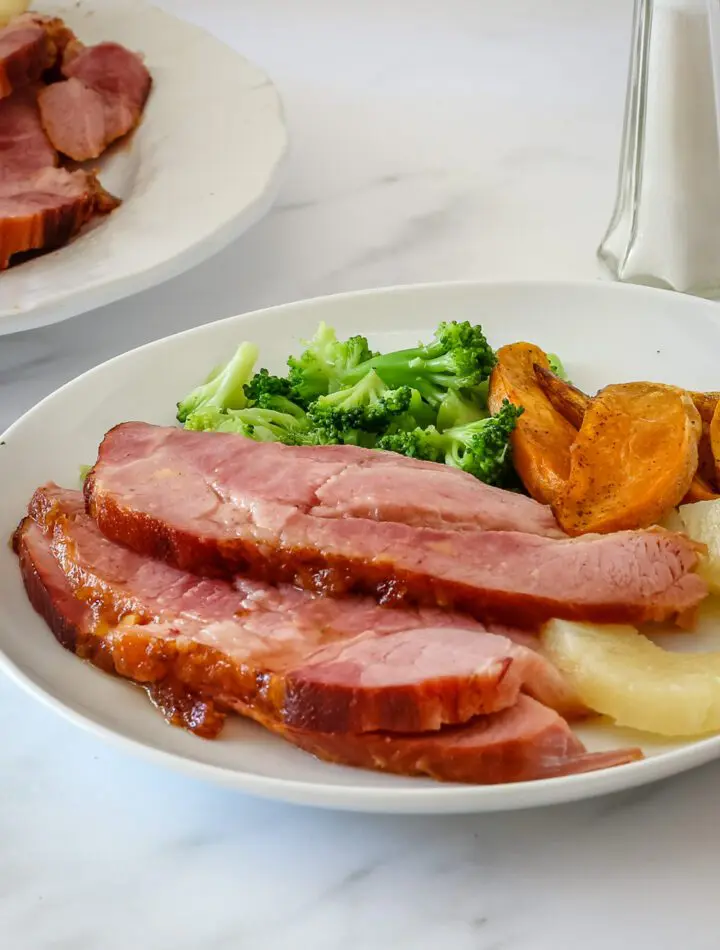 sliced baked ham on a plate with side dishes