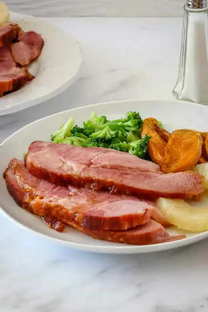 sliced baked ham on a plate with side dishes