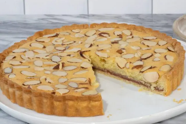 bakewell tart sliced showing the layer of raspberry jam and perfectly cooked crust