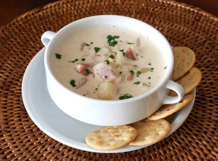 A bowl of clam chowder with crackers