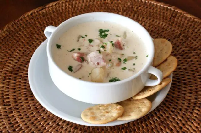 A bowl of clam chowder with crackers