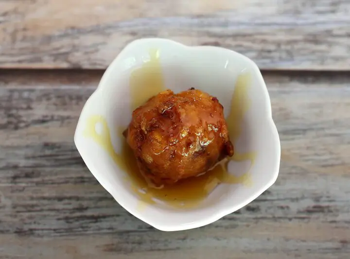 basic corn fritter in a small bowl with golden syrup