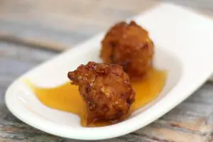 corn fritters on a small serving plate with syrup