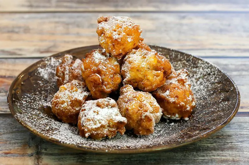 deep-fried corn fritters on a plate, dusted with powdered sugar.