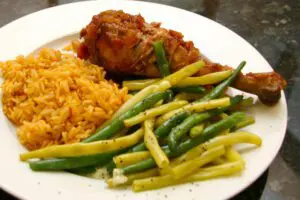 baked turkey legs with barbecue sauce, on a plate with rice and vegetables.