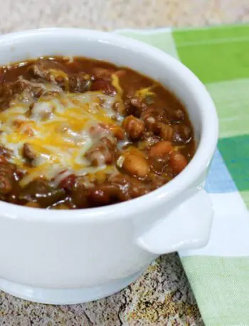 beef and beans with cheese in a bowl with napkin on the side