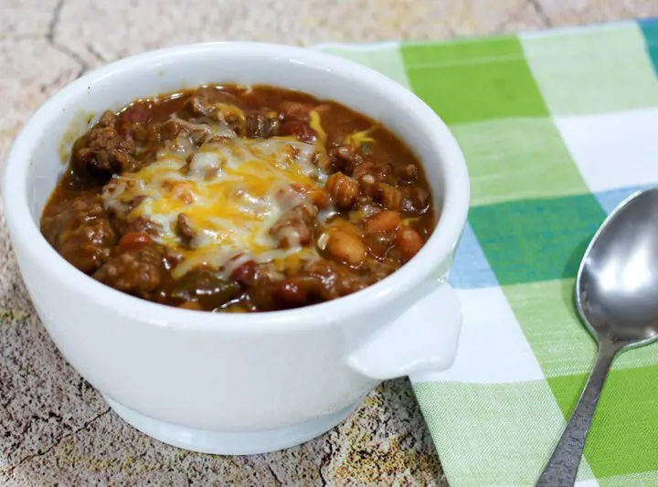 beef and beans with cheese in a bowl with napkin on the side