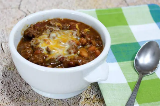 beef and beans with cheese in a bowl with napkin on the side