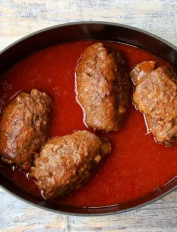 german beef rouladen, beef rolls with pickles and vegetables, in a dutch oven