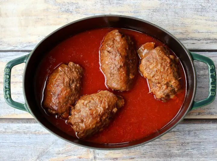 german beef rouladen, beef rolls with pickles and vegetables, in a dutch oven