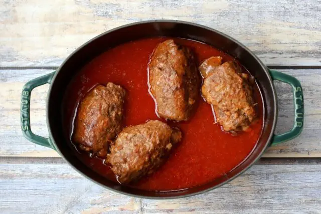 german beef rouladen, beef rolls with pickles and vegetables, in a dutch oven