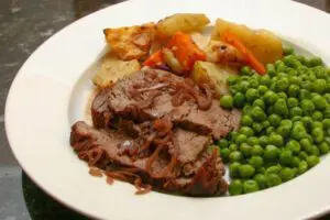 roast beef tenderloin on a plate with red wine sauce and root vegetables