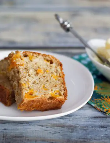 this peach bread on a plate, sliced, with butter on the side