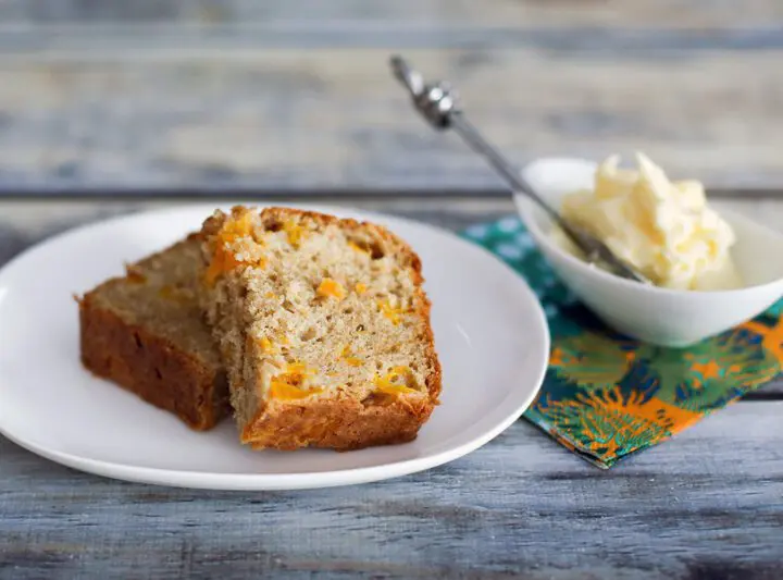 this peach bread on a plate, sliced, with butter on the side