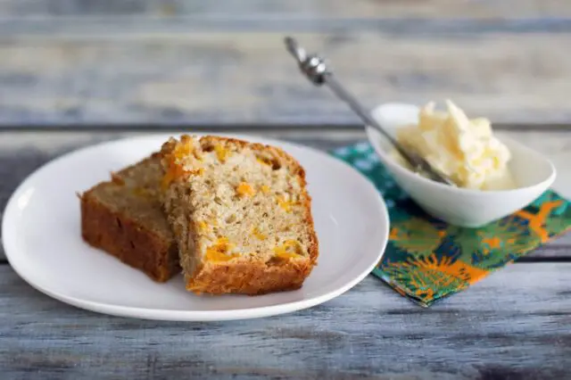 this peach bread on a plate, sliced, with butter on the side