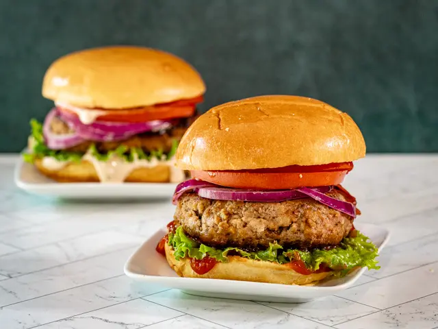 Turkey burgers in brioche buns with toppings and condiments.