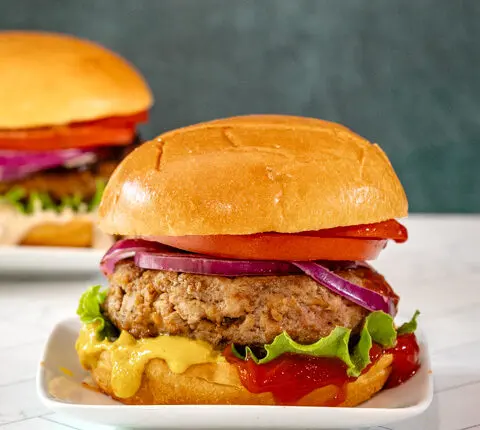 An assembled turkey burger with toppings and condiments.