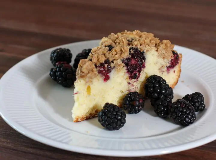 blackberry crumb cake on a plate with fresh blackberries